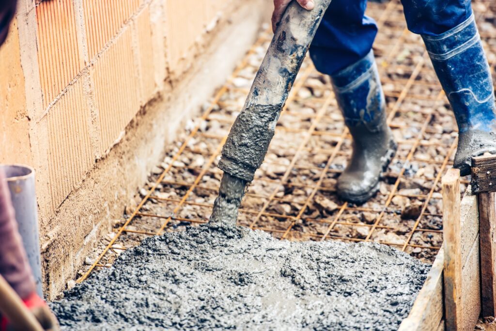 close up of industrial worker pouring cement or concrete with automatic pump tube