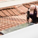 Worker fixing solar water heater on roof during maintenance